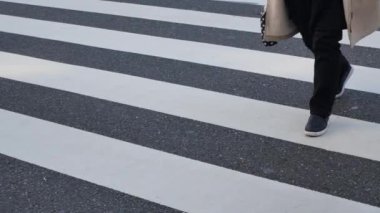 low angle view to the asphalt street at zebra crossing area at intersection while crowded of people pedestrian walking crossing ginza shopping street in Tokyo city of japan in winter day time