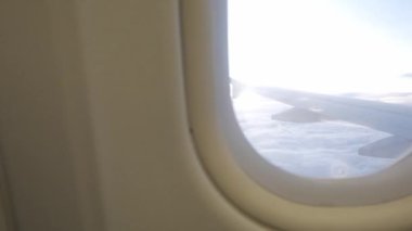 Gün batımında bulutların üzerinde gökyüzüne tırmanırken uçağın penceresinden geçen manzara, doğal ulaşım tatil arka planı.