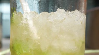 Bir bardak mojito kokteyline odaklan limon ve nane yapraklı alkol içerken yakın plan içmek için pipet kullan, kokteyl iç.