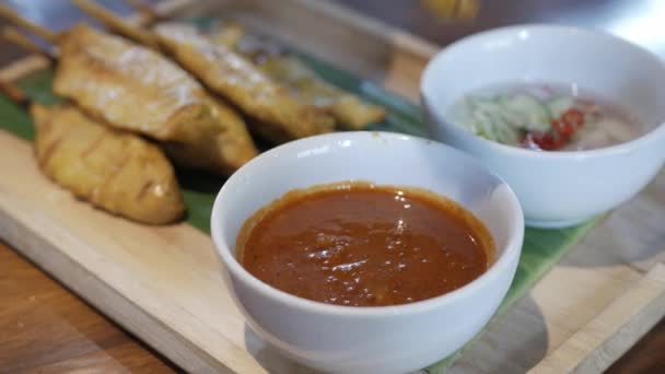 シンガポールやマレーシアの伝統的な料理スタイルのプレートにサテイ スワワーのチキンを手で飾る 食事や軽食の前に前菜のためのソースに浸る — ストック動画