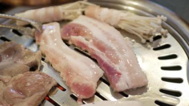 Kore 'nin geleneksel kömür tavası sobası Galbi' de ızgara yapılırken domuz etine özel bir bakış açısı. Sobanın üstünde Kore usulü sebzeli ızgara et.