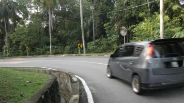 natural view of the local road outdoor through the tropical rain tree forest in Kuala lumpur,Malaysia suburb under sunshine day , southeast asia landscape road