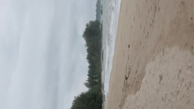 Sahil kıyısı beyaz kum pürüzsüz plajın dikey videosu. Turkuaz tropikal su denizi ve biraz dalga, tropikal doğa yaz manzarası.
