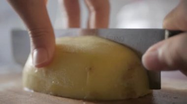 Tahta kesme tahtasındaki taze patatesi kesmek için bıçak kullanmak, pişirmeye hazır olmak.