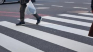 Düşük açılı görüntü bulanıklaşır. Japonya 'nın Tokyo şehrinde kış günü, yaya geçidinde Ginza alışveriş sokağından geçen kalabalıktan oluşan kavşaktaki zebra kavşağındaki asfalt sokağa bakar.