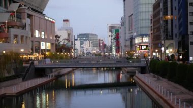 17 Kasım 2022 Fukuoka, Japonya. Gündüz Fukuoka 'da reklam panoları ve reklam panoları olan modern binalar arasında arabalar ve insanlar trafiği yürütüyor. Japonya 'da sokak manzarası