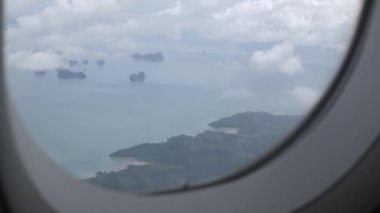 Tayland 'ın güneyinde, Phuket' in tropikal seyahat noktasında, okyanus kıyısındaki güzel bulutların üzerinde yoğun bir bulutla uçağın penceresinden bakmak.