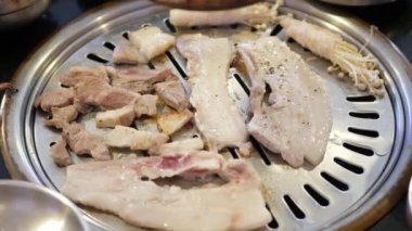 Kore 'nin geleneksel kömür tavası sobası Galbi' de ızgara yapılırken domuz etine özel bir bakış açısı. Sobanın üstünde Kore usulü sebzeli ızgara et.