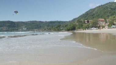 Şubat 10.2024.Phuket, Tayland. Patonng sahilinde güneşli öğleden sonra deniz sahili beyaz kumsala vuruyor. Güneşli bir günde ünlü beyaz kumsalın doğal deniz manzarası.