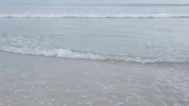 Sabahın erken saatlerinde deniz kıyısı üzerindeki doğal manzara. Deniz dalgaları beyaz kumsala çarpıyor. Dalgalar pürüzsüz beyaz kumsala çarpıyor..