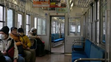 29.2024.Kyoto, Japonya manzaralı yerel japan kyoto treninin içi yolcularla doluyken kışın çam ağaçlarının arasından Kurama Dağı 'na kar yağar.