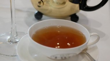 Beyaz seramik fincanın içini İngiliz siyah çayıyla doldurun öğleden sonra çayını dinlenme zamanı için için için servis edin, öğleden sonra taze çay seti restoran arka planında servis edilsin.