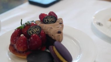 24 Şubat 2024 Bangkok, Tayland. Seçici odak noktasını kapatarak tatlı tatlı pastası, turta ve öğleden sonraki çay seti için beyaz seramik tabakta kurabiyeler.