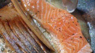 Somon bifteği kızartma tavasına konur ve kızarmış taze somon balığını çıtır çıtır cilt için tereyağında kızartılır. Evdeki mutfakta taze somon balığı bifteği pişiriyorum..