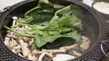 Shabu shabu Japon usulü haşlanmış sıcak suki yaki çorbasının içine sebze ve et koyarken yakın çekim yapın. Japon usulü Asya usulü sağlıklı domuz eti ve Shabu yemeği pişirmek.