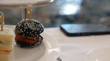 Kanepe sandviçi için beyaz tabakta seçici odak noktasını kapatırken, öğleden sonra çay saatinde kanepe kapıp yemek yemek için el kullanılıyor. Şehir hayatı dinlenme zamanı.