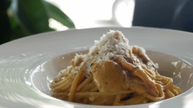 Bir tabak İtalyan carbonara spagetthi 'sine yakın, üstünde parmesan peyniri ile İtalyan mutfağında beyaz peynir sosu, akşam yemeğinde yemeye hazır, ev yapımı İtalyan yemeği.