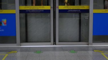 Metro istasyonunun düşük açılı görüntüsü, kapı kapanırken ve tren metro metro istasyonundan kalkışa hazırken kalabalık saatte, doğu Asya treni toplu taşımacılık sesiyle...