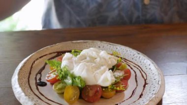 İtalyan usulü salata yemek için çatal ve bıçak kullanıyoruz. Üstünde ev yapımı mozzarella peyniri var. Akşam yemeği için aperatif olarak.