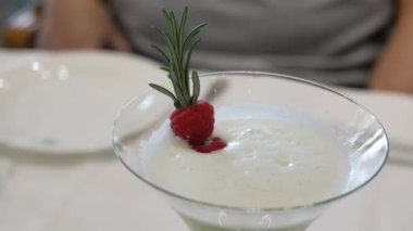 Seçici manzarayı bir bardak çalkalanmış meyve kokteyline yakın açık mavi renkli ahududu ve biberiye süslemeli restoranda içilmeye hazır.