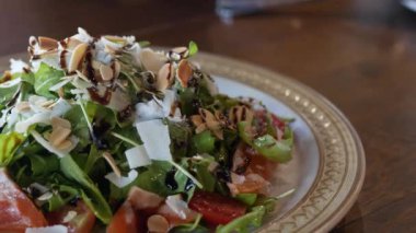 Akdeniz salatasına yakın bir tabakta badem ve peynirle kaplı ev yapımı dilimlenmiş ve akşam yemeğinde aperatif olarak yenmeye hazır, Akdeniz meze salatası.