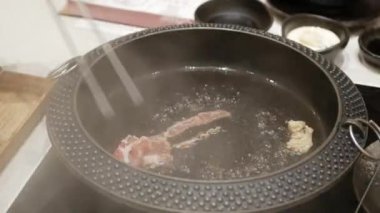 Shabu shabu Japon usulü haşlanmış sıcak suki yaki çorbasının içine sebze ve et koyarken yakın çekim yapın. Japon usulü Asya usulü sağlıklı domuz eti ve Shabu yemeği pişirmek.