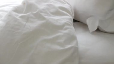 Sabahları yatak odasında yatak örtüsü ve yastık hazırlayan bir adam otel odasında makyaj yaparken beyaz çarşaf beyazı yatak manzarası.