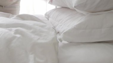 Sabahları yatak odasında yatak örtüsü ve yastık hazırlayan bir adam otel odasında makyaj yaparken beyaz çarşaf beyazı yatak manzarası.