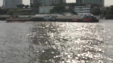 Odakta bulanıklaşan parlak güneşli ışıltılar sabah dalgaları ve su yüzeyinde sıcak renkli yansıması olan tropikal bir nehirde kıyıya vuran dalgalar..