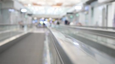 Havaalanı kalkış terminalindeki yürüyen merdiven için seçici bir odak noktası. Arka planda bulanık manzarası olan, kalabalık bir yolcuyla birlikte terminalin içinde.