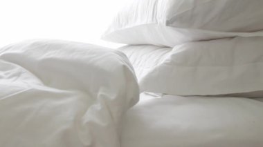 Sabahları yatak odasında yatak örtüsü ve yastık hazırlayan bir adam otel odasında makyaj yaparken beyaz çarşaf beyazı yatak manzarası.