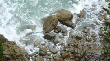 Deniz ve kayalıklardaki hava manzarası turkuaz su dalgası yaz tatili için kayalıklara vururken tepeden bakıldığında okyanus mavisi dalgalar kayalık bir dağın yüksek uçurumunda kırılıyor..