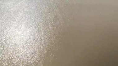 Yaz tatilinde deniz dalgaları sahile vururken beyaz kumsal sahili tepeden aşağıya doğru görünüyor. Doğal arka plan köpüklü okyanus dalgaları kumsala vuran kumları temizliyor.