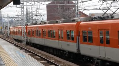 27 Ocak 2024. Osaka, Japonya. Yerel tren istasyonunu, Osaka dışındaki yerel şehrin arka plan görüntüsüyle gündüz vakti tren istasyonuna yaklaşırken görüntüle