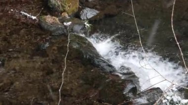 Doğal dondurucu doğa arasındaki küçük nehir kanalının manzarası. Çimen tarlasının yüzeyine ilk kar yağışı ve nehrin her iki yakasında da kayalık.