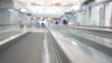 Havaalanı kalkış terminalindeki yürüyen merdiven için seçici bir odak noktası. Arka planda bulanık manzarası olan, kalabalık bir yolcuyla birlikte terminalin içinde.