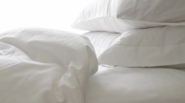 Sabahları yatak odasında yatak örtüsü ve yastık hazırlayan bir adam otel odasında makyaj yaparken beyaz çarşaf beyazı yatak manzarası.