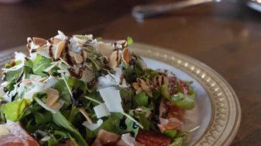 Bir tabak Akdeniz salatasına yakın, üzerinde badem ve peynirle dilimlenmiş ve akşam yemeğinde aperatif olarak yenmeye hazır.