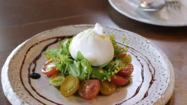 Üstü taze mozzarella peyniriyle kaplı bir tabak İtalyan salatasına yakın akşam yemeğinde aperatif olarak yenmeye hazır.