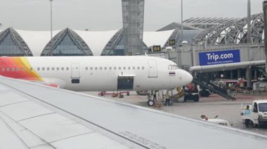 Uçak Suvarnabhumi havaalanı terminalinden ve hava trafik kontrol kulesinden kalkışa hazırlanırken uçak penceresinden bakın.