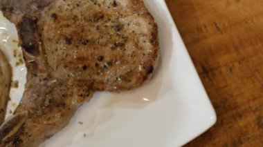 Yemek saatinde yemek için Tayland usulü restoranda servis edilen bir tabakta tavuk bifteği kesmek için çatal ve bıçak kullanırken, akşam yemeğinde domuz ve tavuk bifteği.