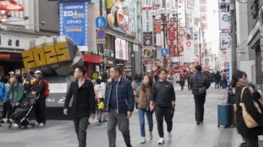January28,2024.Osaka, Kansai, Japonya. Gündüz vakti Dontonburi 'de gece hayatı alışveriş caddesinde birçok insan yayalar üzerinde 2025 Fuarı ile alışveriş yapıyor.