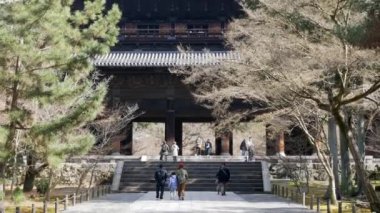 Kyoto 'daki Nanzenji Tapınağı' nın ana antik ahşap kapısına giden Japonya 'da Ocak 26.2024 Kyoto, kışın düşen akçaağaç ve çam ağaçlarıyla çevrili arazi yolu.