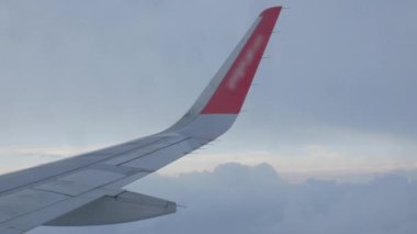 Bulutların üzerinde bulutların üzerinde uçarken bulutların üzerinden bulutların üzerinden geçen, bulutların hareket ettiği, yaz tatili arka planında uçağın mavi gökyüzü üzerindeki kanadı ile birlikte uçağın penceresinden bakmak.