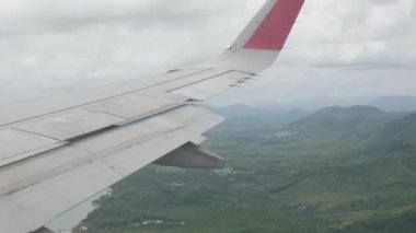 Phuket doğal plajları ve Phanga Körfezi 'ndeki birçok adanın manzarası ile havaalanına inerken kanat manzaralı uçak penceresinden görüş.