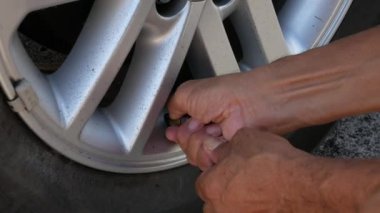 Güneşli bir günde sürücü arabanın lastiğini şişirirken arabanın lastiğini kapat. Hava basıncı göstergesiyle el ele tutuşan hortum ve arabanın lastiğini nitrojen havasıyla doldurmak.