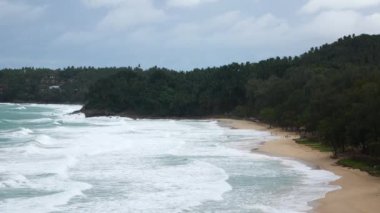 Deniz kumu sahil koyunun hava manzarası güçlü bir dalga ile Phuket tropikal tatil yerindeki beyaz kumsal sahili vurdu yaz tatilinde ve arka planda dağ aralığı