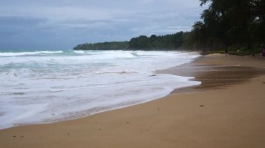 Phuket 'teki beyaz deniz kumlu sahile vuran güçlü dalgalarla deniz kıyısı manzaralı tropikal seyahat tatili yağmurlu, bulutlu, sert rüzgarlı strom geliyor.