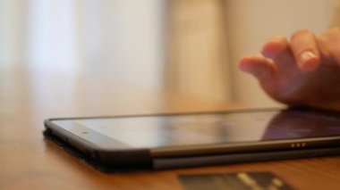 Asyalı bir adam online alışveriş ürünü satın almak için akıllı telefon tableti kullanırken kredi kartı ya da banka kartıyla, evde online alışveriş teknolojisi yaşam tarzı