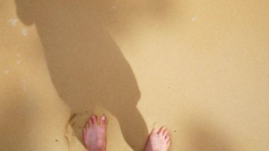 Yaz tatilinde deniz kumsalında çıplak ayakla yürümek. Deniz dalgaları ayaklara çarpıyor. Yaz tatili, dinlenme, doğal tatil.